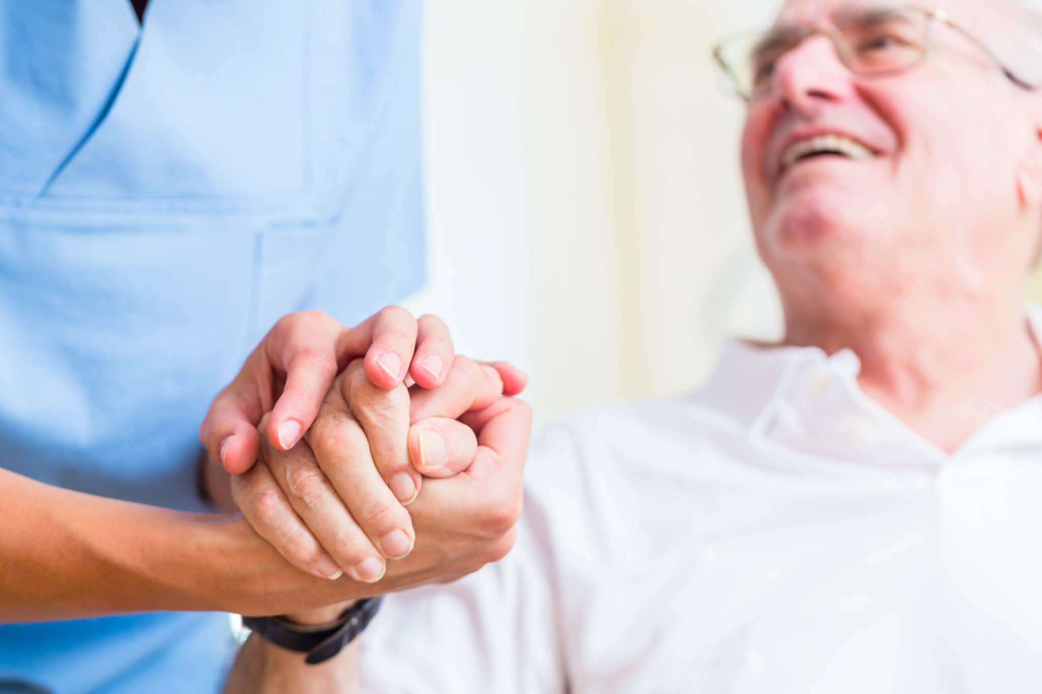 Nurse holding hand of senior man in rest home
